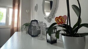 A room with a white table, a potted plant, a decorative mirror, and a wall-mounted light fixture. - Apartments Mavi - Two-bedroom Apartment With Terrace and City View (Dubrovnik)