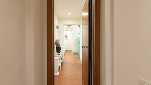 A hallway with a tiled floor, a white door, and a light blue wall. - Pitti Suite (Florence)