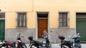 Three scooters parked on a street in front of a building with a green door and barred windows. - Pitti Suite (Florence)