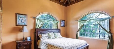 Un dormitorio con una cama de madera, una mesita de noche y un ventanal con vistas a la vegetación.