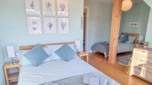 A bedroom with a large bed, a smaller bed, wooden furniture, and artwork on the wall. - Number 10 The Penthouse (Swanage)