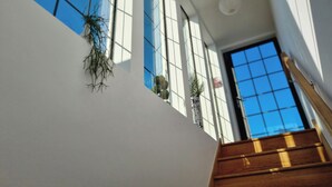 A modern interior with a staircase, large windows, and indoor plants. - Number 10 The Penthouse (Swanage)