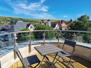 A balcony with a glass railing, two chairs, and a table. - Number 10 The Penthouse (Swanage)