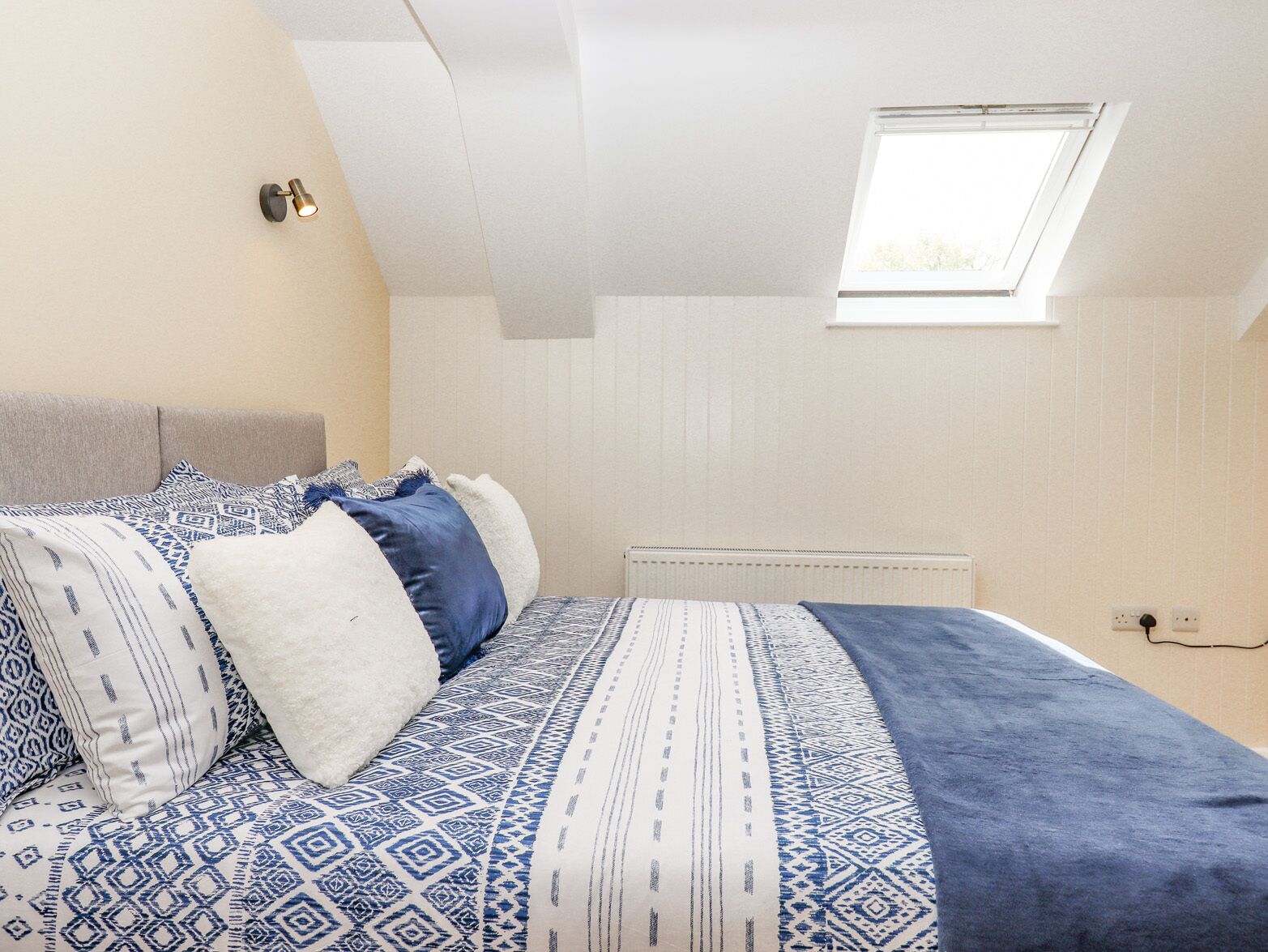 Un dormitorio con cama, tragaluz y radiador.