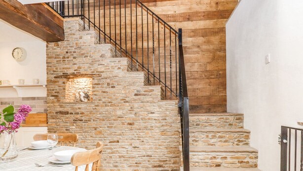Un escalier en pierre avec une rampe métallique menant à un deuxième étage.
