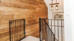 Un mur en bois, une porte en métal et un escalier avec des rampes noires.