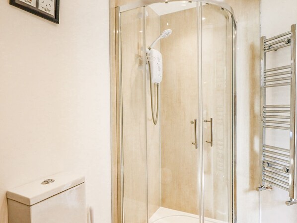 A modern bathroom with a glass-enclosed shower, a toilet, and a towel rack.