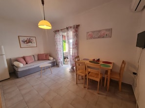 Ein gemütliches Wohnzimmer mit einer Couch, einem kleinen Tisch und einem Essbereich mit Stühlen und einem Tisch.