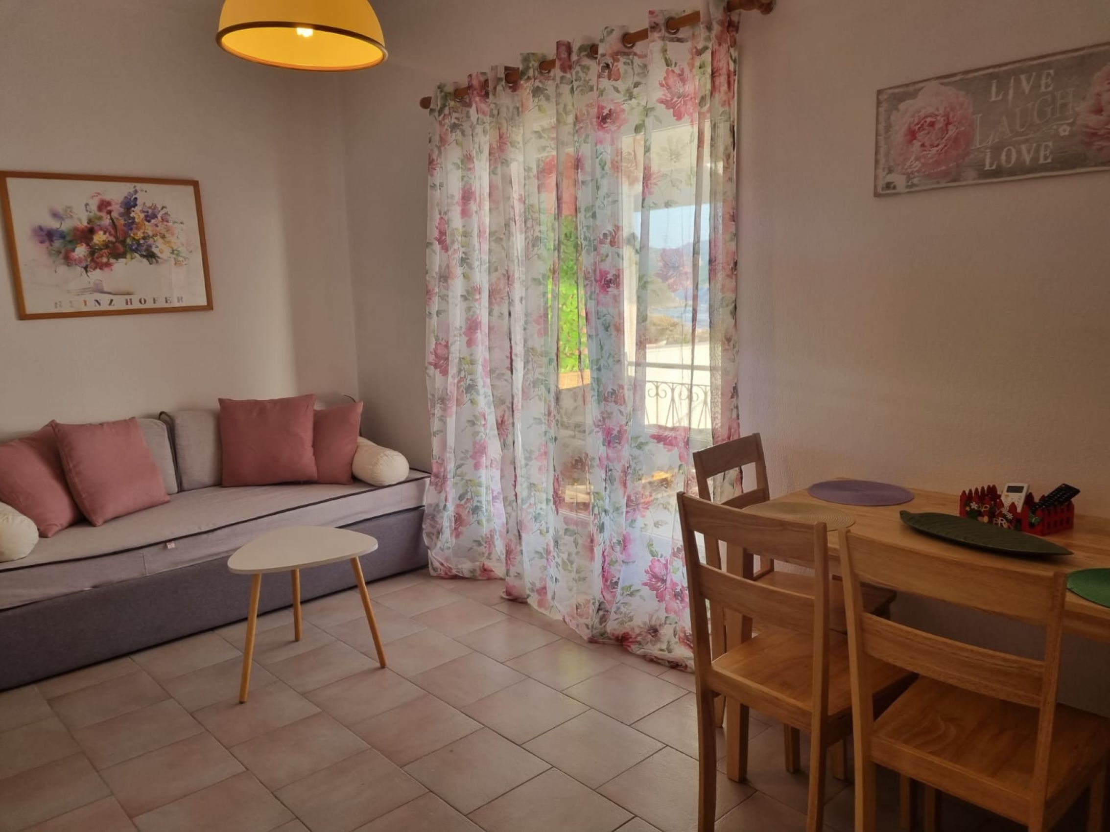 A living room with a sofa, a small round table, and a dining table with chairs.