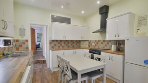 A kitchen with white cabinets, a wooden countertop, and a dining table with chairs. - Brightwater Ground Floor Apartment up to 6 Guests (Scarborough)
