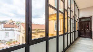 A corridor with large windows and a view of buildings with red-tiled roofs. - Maria s Bright Flat by Wonderful Italy - Duomo 2 (Naples)