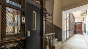 A corridor with a metal gate, a staircase, and a door leading to another room. - Maria s Bright Flat by Wonderful Italy - Duomo 2 (Naples)
