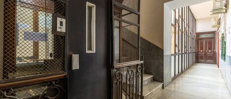 A corridor with a metal gate, a staircase, and a door leading to another room.