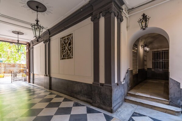 Un couloir doté d’un sol à carreaux, de colonnes et d’éléments d’éclairage décoratifs.