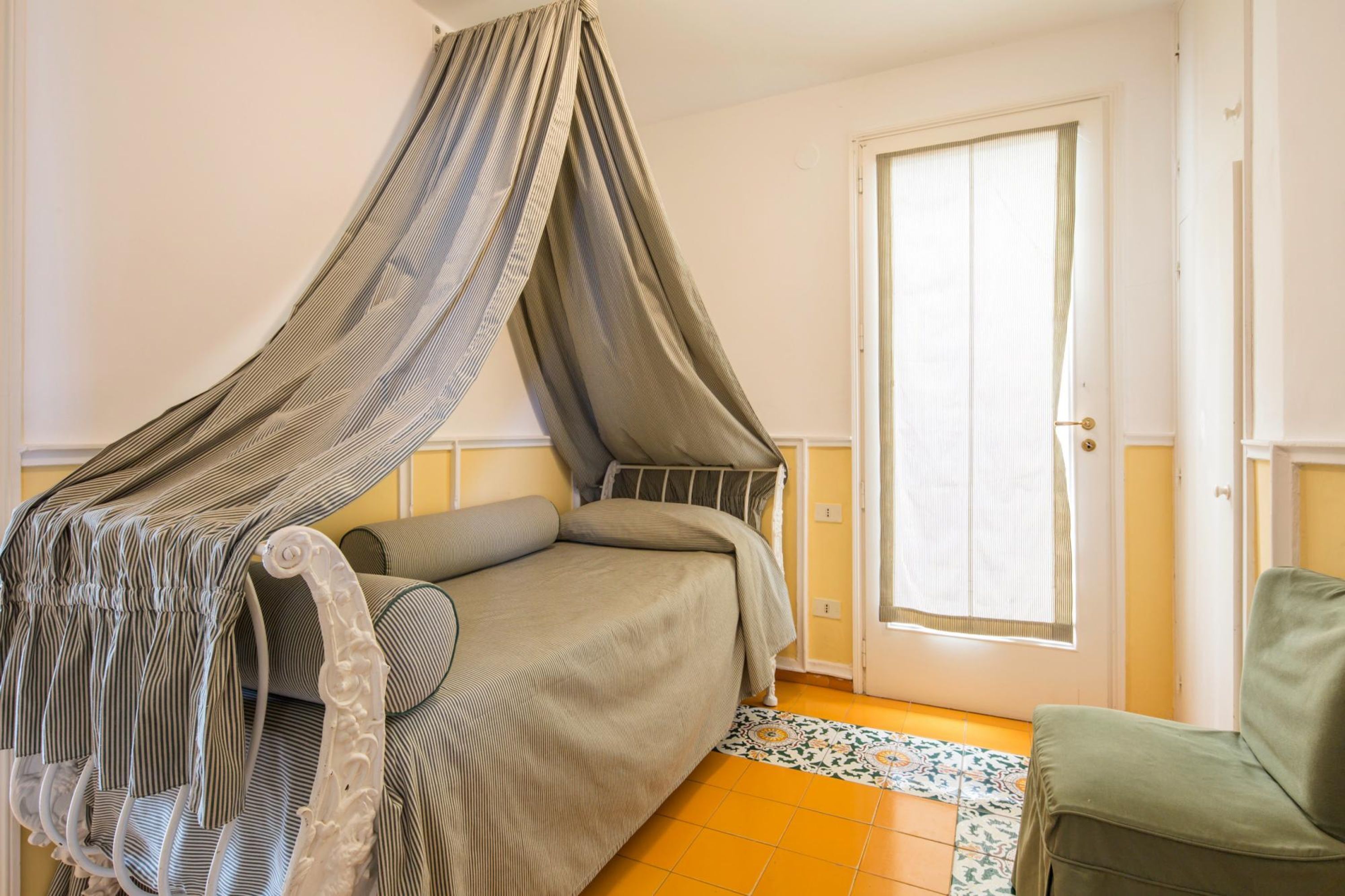 Un dormitori amb un llit amb dosser, una porta amb finestre i una catifa amb disseny.