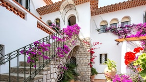 A white building with a stone staircase, a tiled roof, and balconies with flowers. - Villa Bouganville in Massa Lubrense (Massa Lubrense)