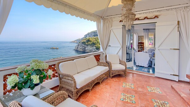 A terrace with wicker furniture, a view of the sea, and a chandelier. - Villa Bouganville in Massa Lubrense (Massa Lubrense)