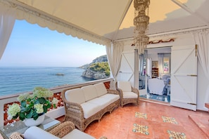 A terrace with wicker furniture, a view of the sea, and a chandelier. - Villa Bouganville in Massa Lubrense (Massa Lubrense)
