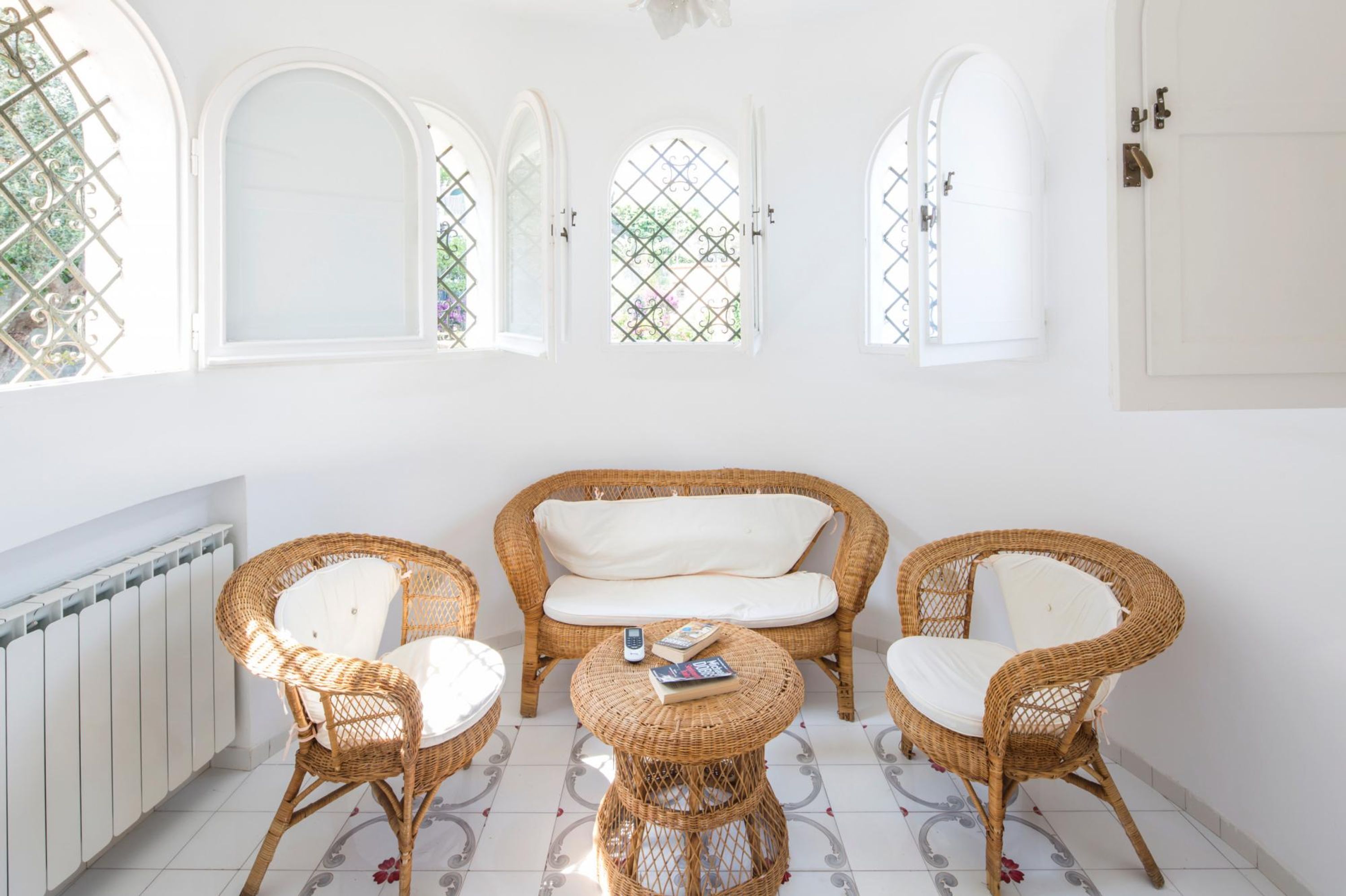 A room with a wicker sofa and chairs, a small round table, and a radiator.