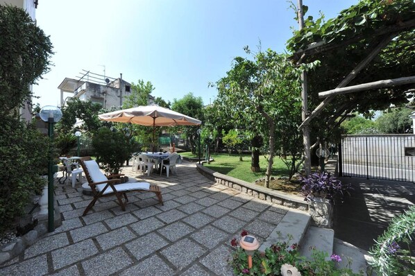 Ein Garten mit Terrassenbereich, Tisch, Stühlen und einer Pergola.
