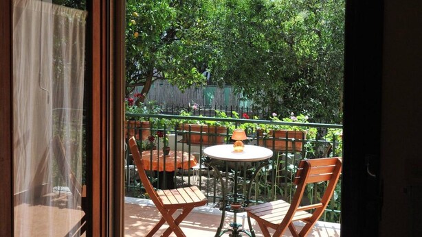 Eine Terrasse im Freien mit Tisch und Stühlen, Blick auf einen Garten und eine Holzlattenzaun.