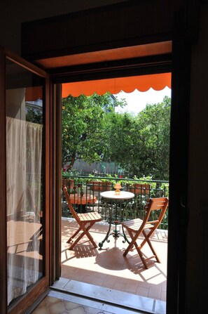 Eine Terrasse im Freien mit Tisch und Stühlen, Blick auf einen Garten und eine Holzlattenzaun.