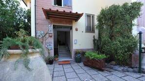 Ein Innenhof mit Steinpflaster, Blumentöpfen, einer Holzbank und einer Pergola.
