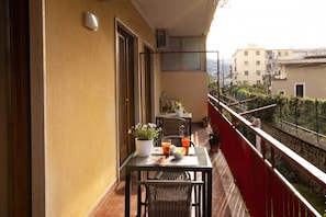 A balcony with a table and chairs, a potted plant, and a view of the cityscape. - Il Quadrifoglio Verde (Sorrento)