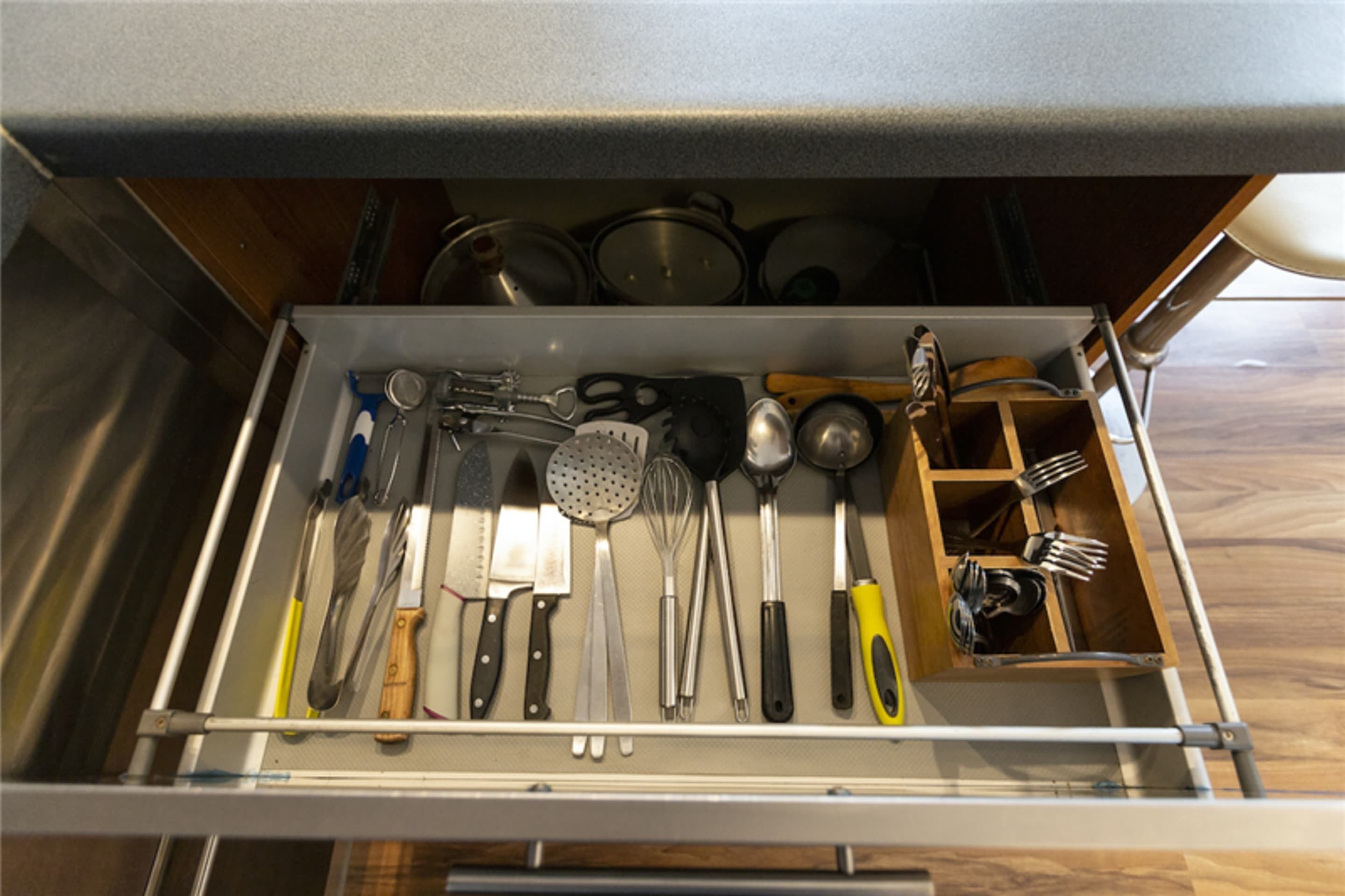A kitchen drawer with utensils and cookware.