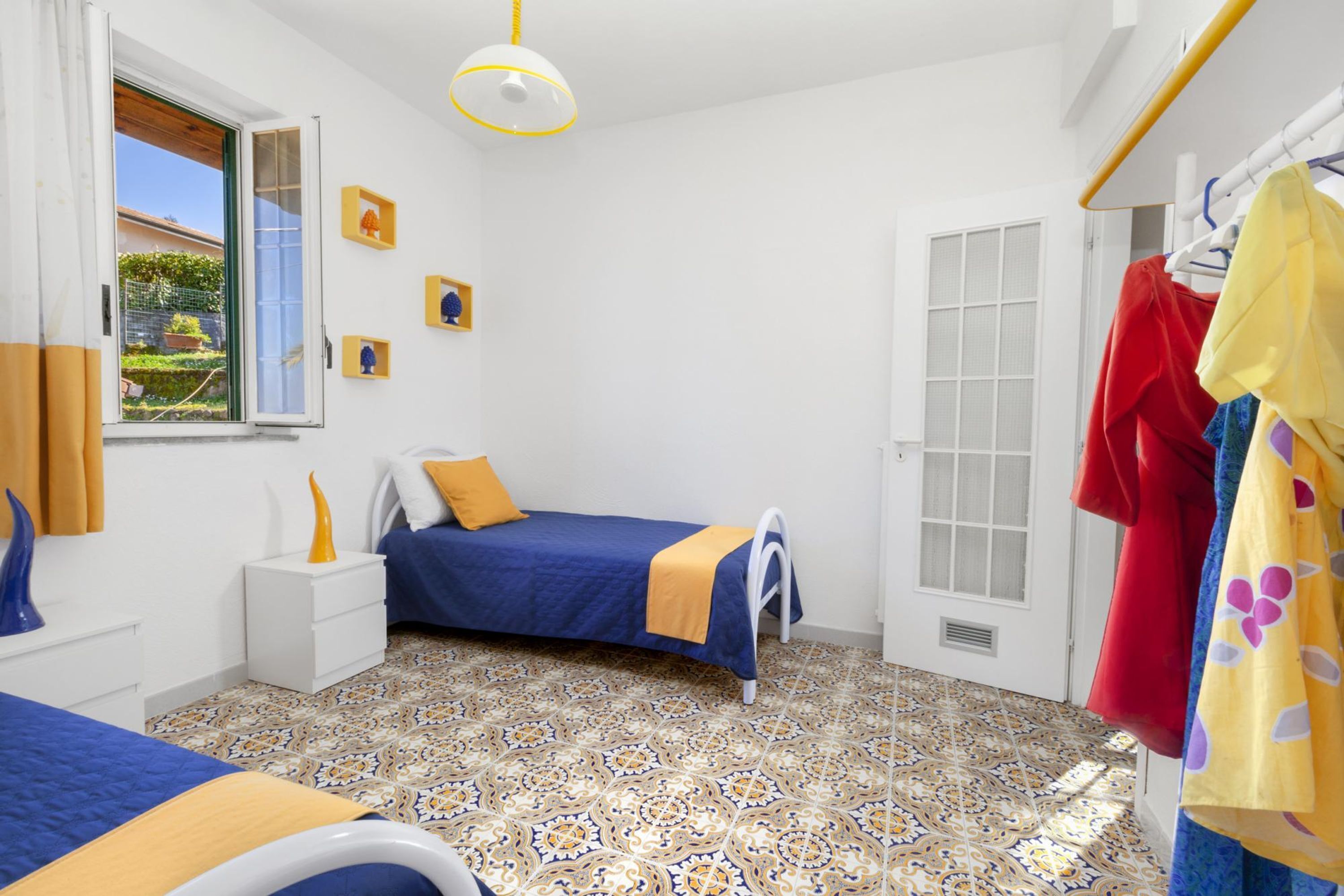 Un dormitorio con cama, mesita de noche, ventana y puerta.