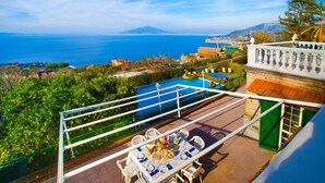 A terrace with a table set for dining, overlooking a pool and a coastal view. - Villa Luisa Jacuzzi Pool (Sorrento)