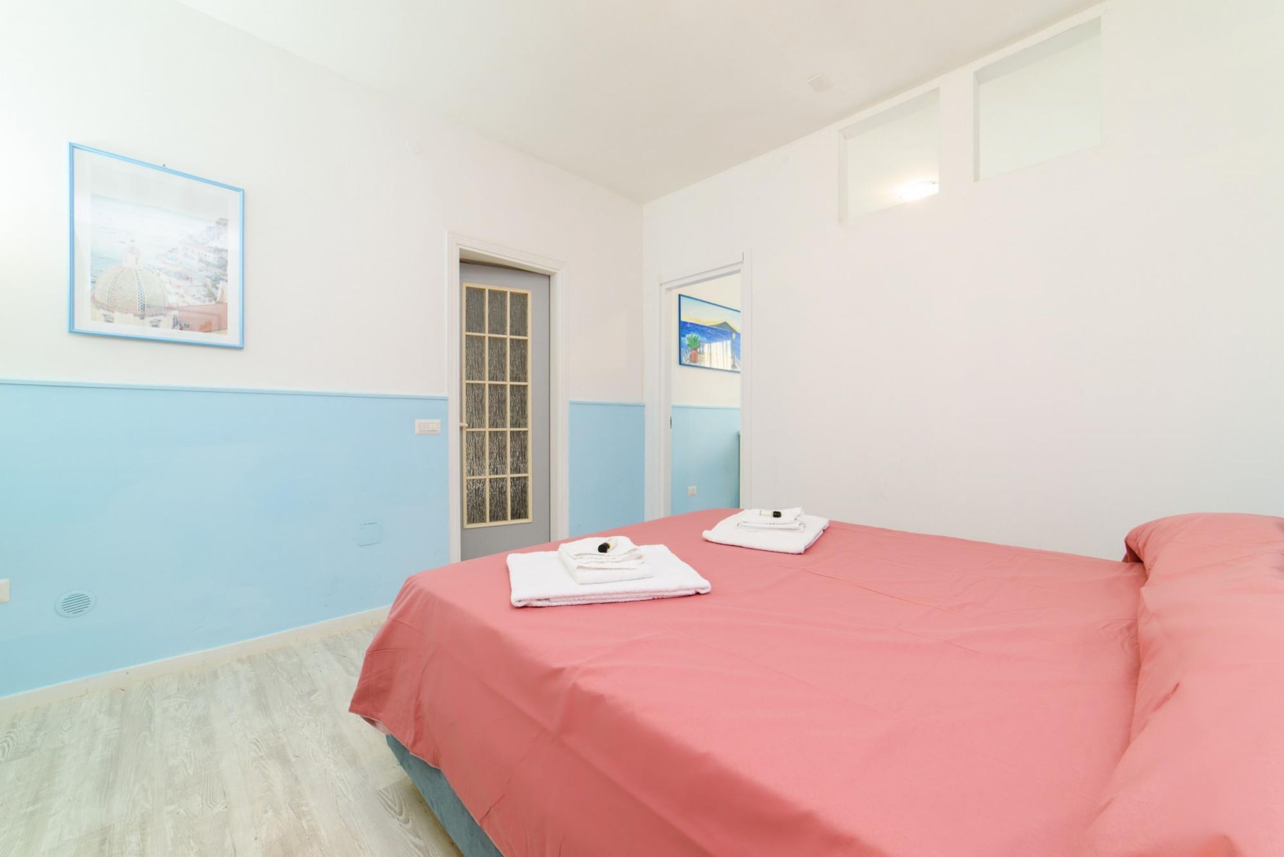 Une chambre à coucher avec un lit, deux serviettes, une fenêtre et une porte.