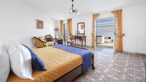 A hotel room with a bed, a desk, a chair, a mirror, and a view of the outside. - Villa Luisa Jacuzzi Pool (Sorrento)