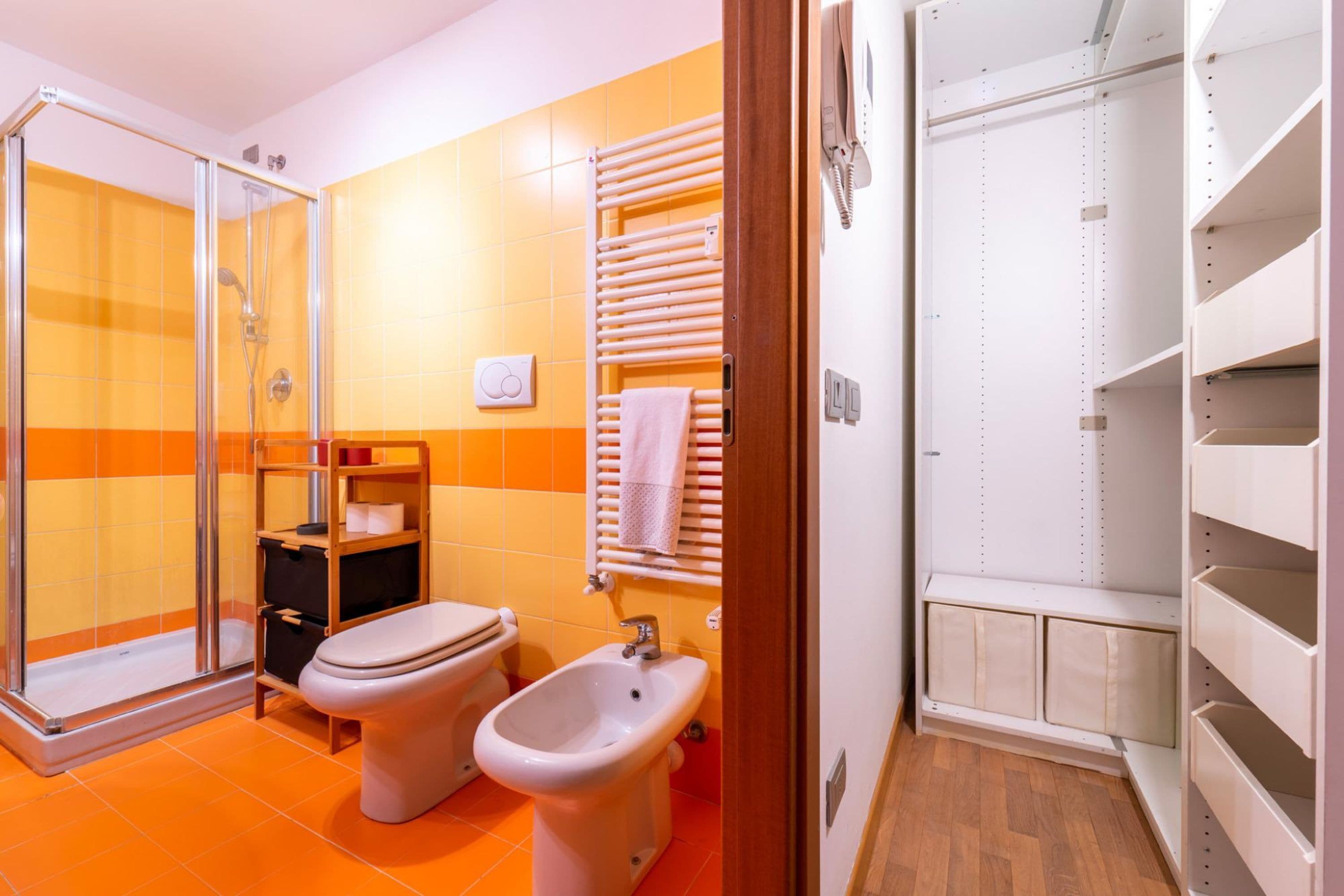 A bathroom with a shower, toilet, bidet, and a towel rack.