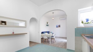 A modern kitchen with a dining area, featuring a wooden countertop, a built-in sink, and a window with a view of greenery. - Maison Jenny in Positano (Positano)