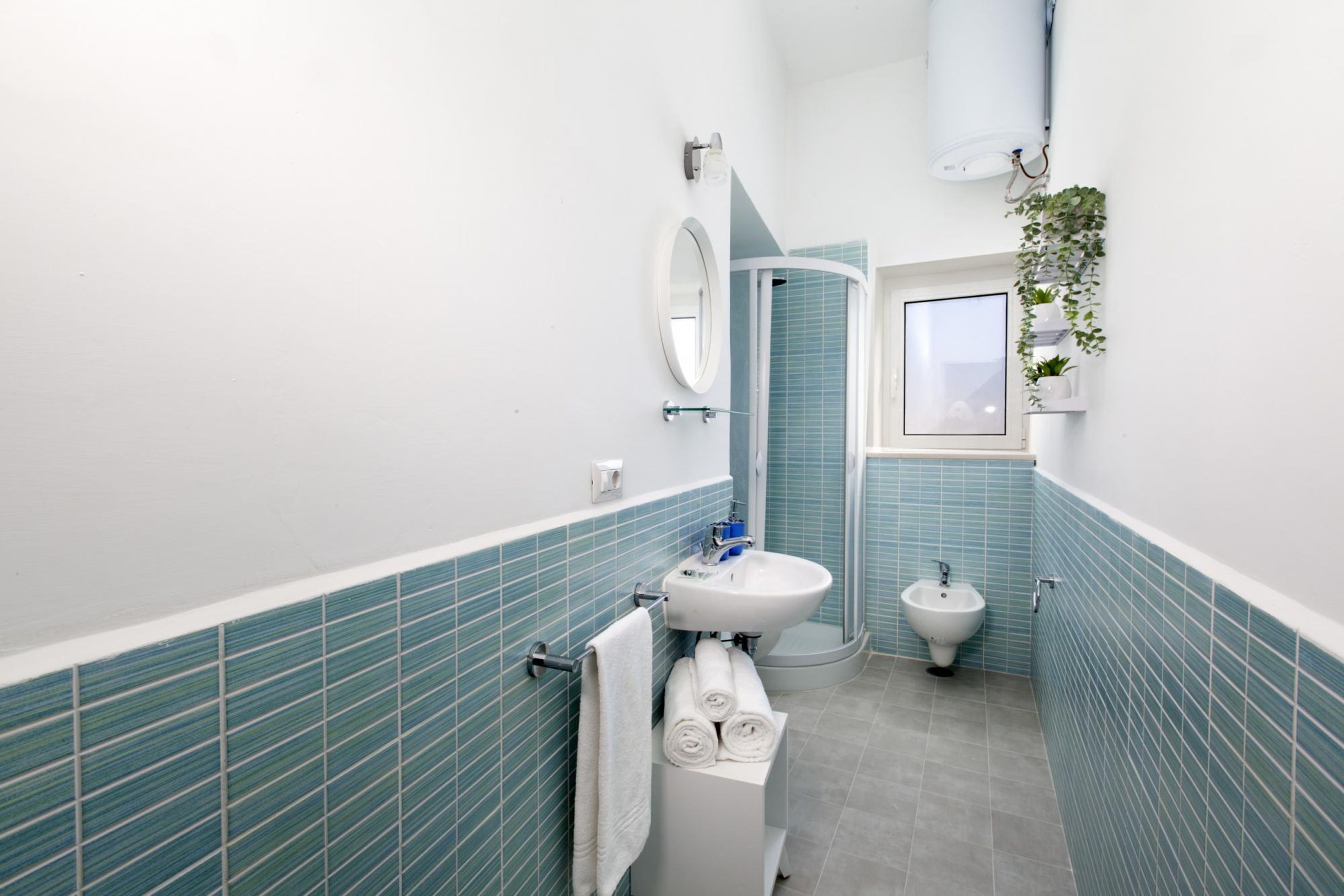 A bathroom with a white sink, a mirror, a bidet, and a towel rack.