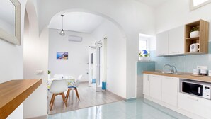 A modern kitchen with white cabinets, a wooden countertop, and a built-in microwave. - Maison Jenny in Positano (Positano)