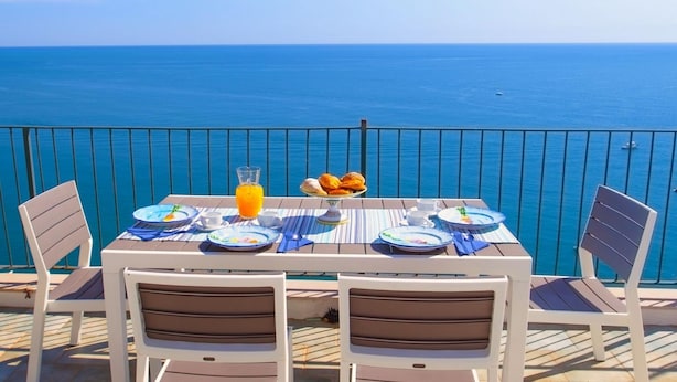 A table set for breakfast with a view of the ocean, white chairs, and a railing. - Maison Jenny in Positano (Positano)