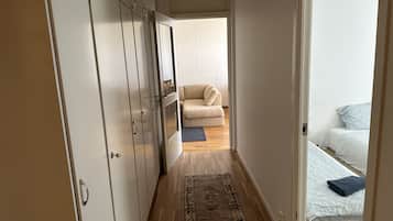 A narrow hallway leading to a bedroom with a bed, a sofa, and a wardrobe.