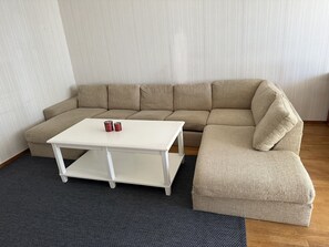 A living room with a beige sectional sofa, a white coffee table, and a matching ottoman. - 3 Room Apartment in Solna (Solna)