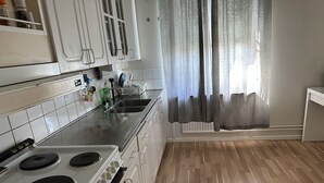 Una cocina con gabinetes blancos, un lavaplatos de acero inoxidable y una estufa.