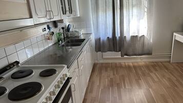 A kitchen with white cabinets, a stainless steel sink, and a stove.