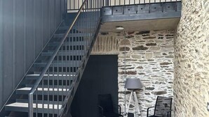 Een trap die leidt naar een balkon met stenen muren en een plafondlamp.