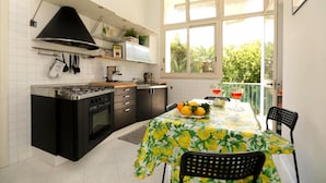 Cozinha com fogão, forno e armários pretos. Há uma mesa de jantar com toalha amarela e cadeiras.