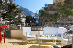 A terrace with wicker furniture, a table, and chairs. - Casa Nonna Mary in Positano (Positano)