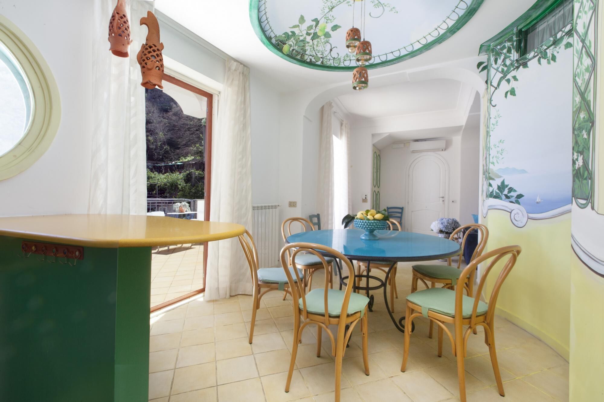 A dining area with a round table, six chairs, and a view of the outdoors.