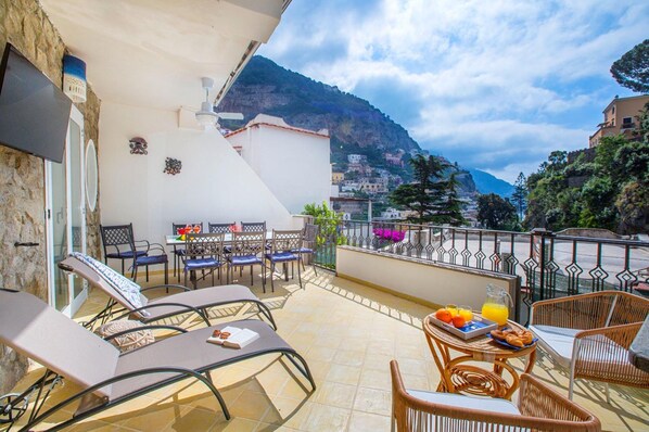 Une terrasse avec des fauteuils confortables, une table où est servi le petit-déjeuner et une vue imprenable sur les montagnes.