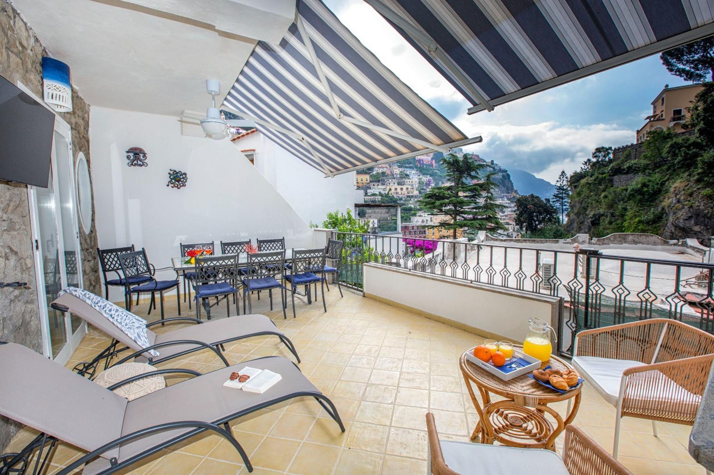 A balcony with lounge chairs, a table with breakfast, and a scenic mountain view.