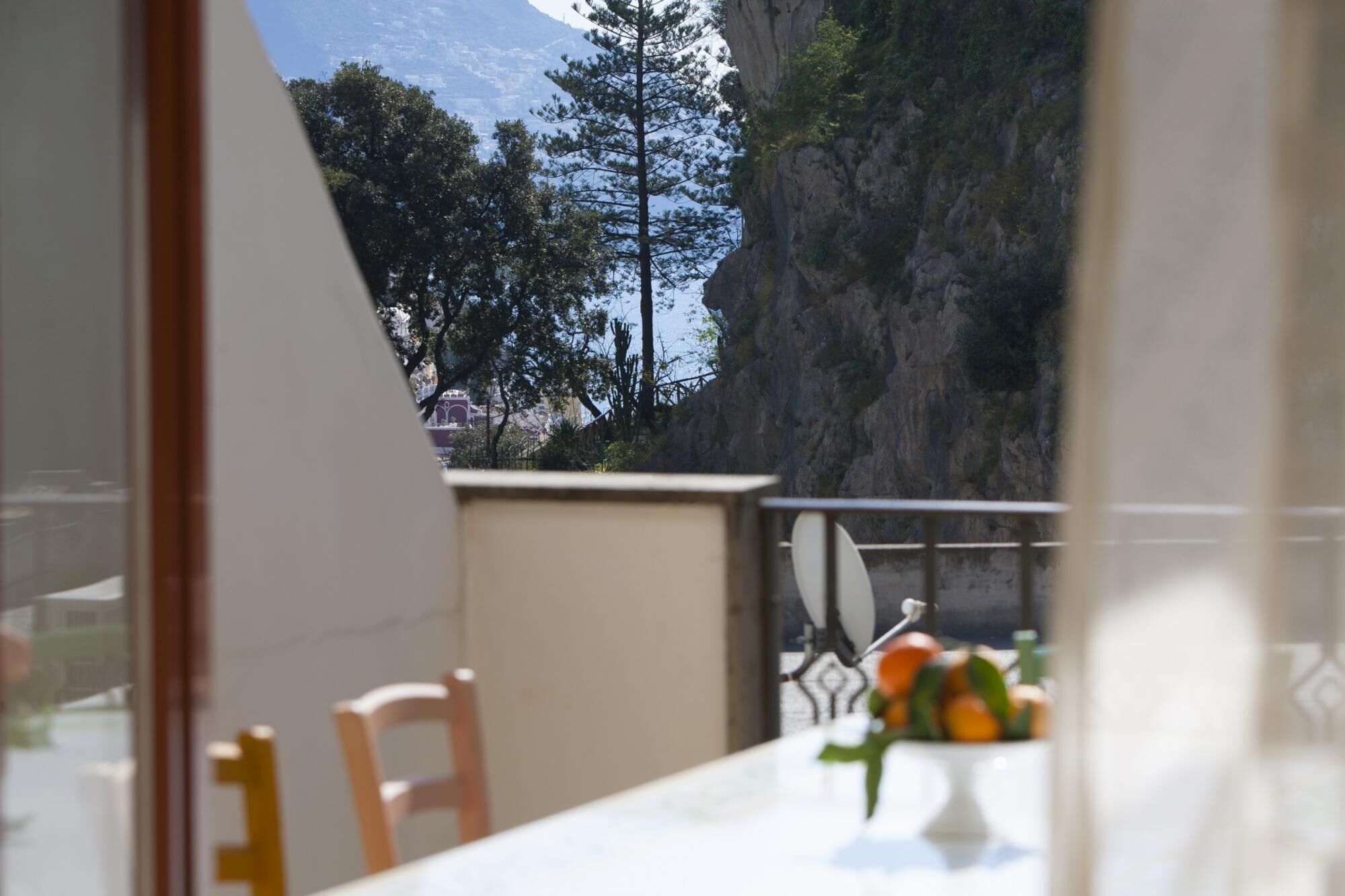 Een balkon met uitzicht op een bergachtig landschap en een tafel met een bloevas.