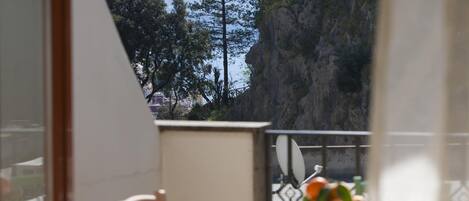 Een balkon met uitzicht op een bergachtig landschap en een tafel met een bloevas.
